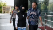 Bupati Sukoharjo Etik Suryani mengenakan hijab hitam dan masker dikawal petugas saat tiba di Gedung Merah Putih KPK.