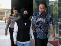 Bupati Sukoharjo Etik Suryani mengenakan hijab hitam dan masker dikawal petugas saat tiba di Gedung Merah Putih KPK.