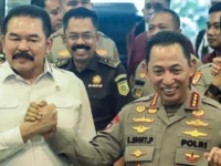 Foto bersama Jaksa Agung ST Burhanuddin berbaju putih dan Kapolri Jenderal Listyo Sigit Prabowo berseragam dinas Polri sedang berjabat tangan erat, didampingi jajaran pejabat kepolisian dan kejaksaan di dalam ruangan dengan latar pintu kaca.