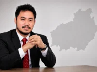 Damai Alam Usop, penyusun kajian akademis RUU Otsus Kalteng, dengan latar siluet peta Kalimantan Tengah sebagai ilustrasi penguatan kewenangan daerah.