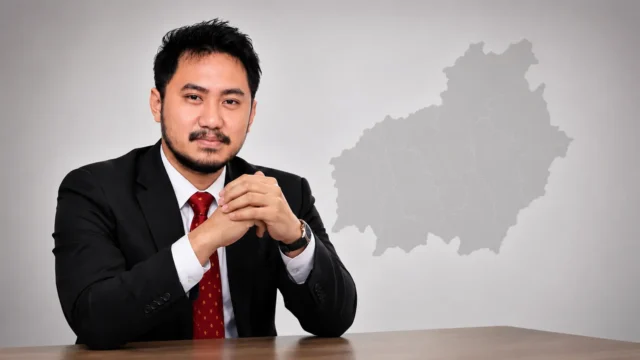 Damai Alam Usop, penyusun kajian akademis RUU Otsus Kalteng, dengan latar siluet peta Kalimantan Tengah sebagai ilustrasi penguatan kewenangan daerah.